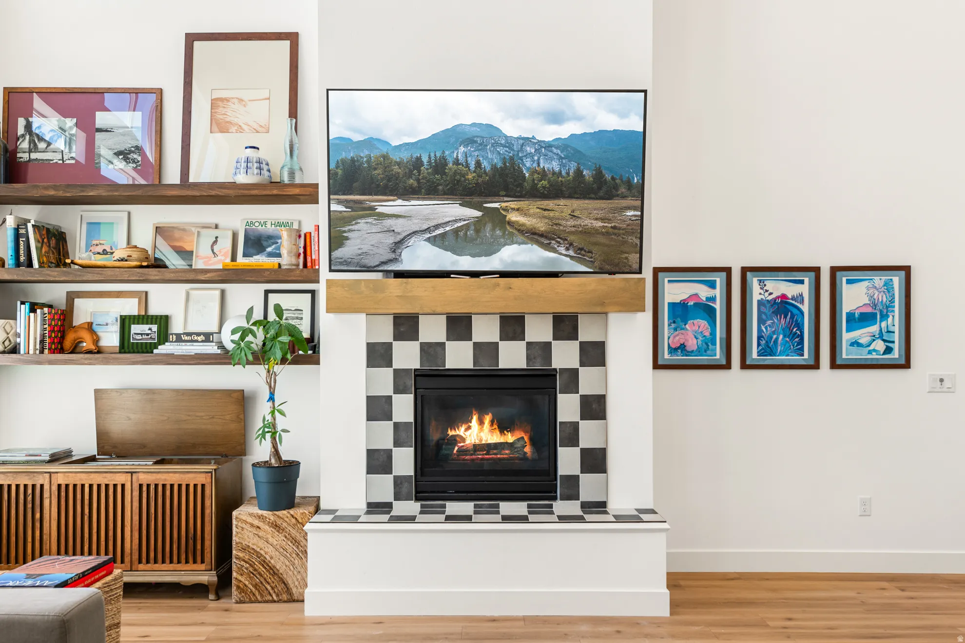Fireplace with black and white checkerboard tile surround, a natural wood mantel, and wood-finish flooring