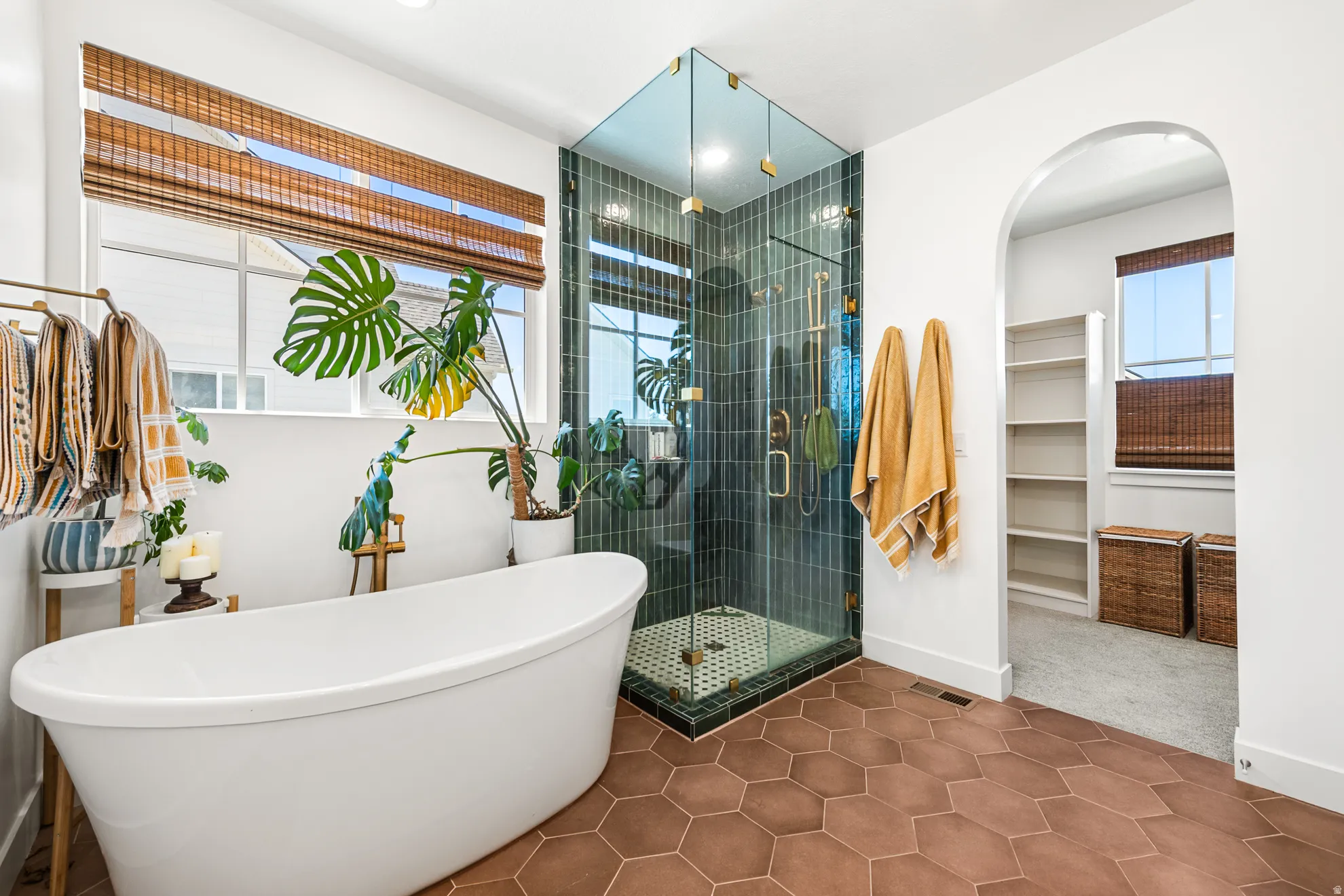 Freestanding soaking tub and glass-enclosed shower with vertical dark tile