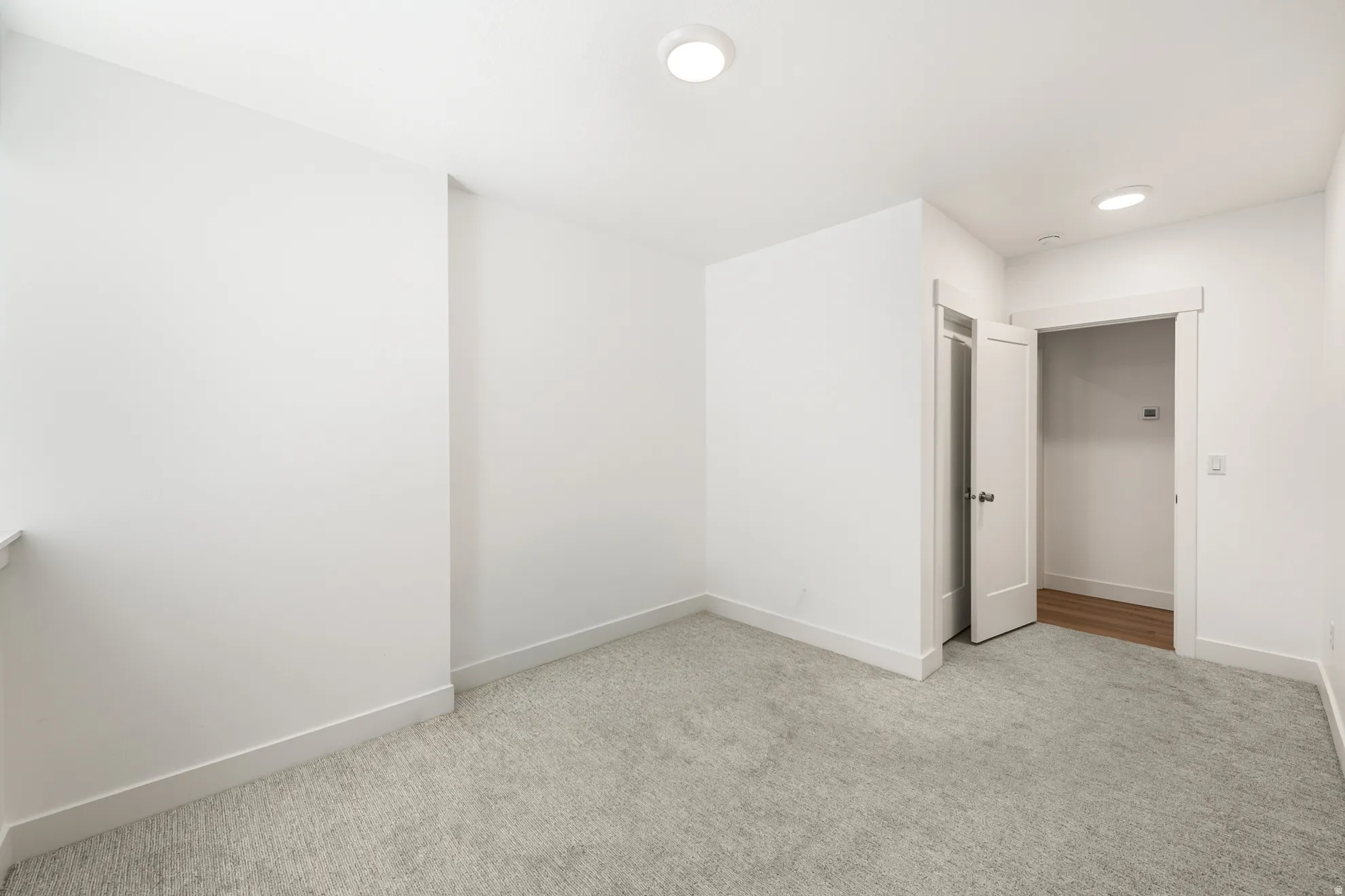 Bright interior space featuring light-colored carpeting and white walls