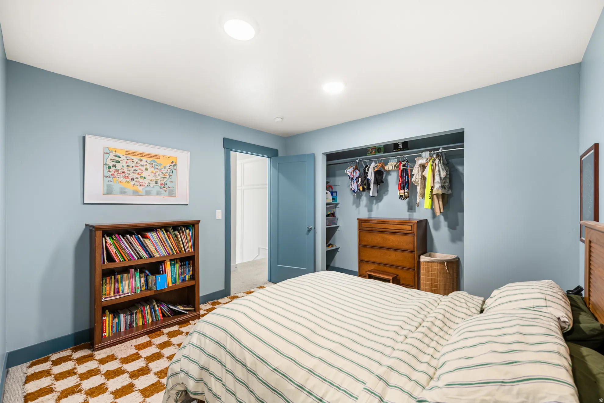 Bedroom featuring a built-in closet with shelving and hanging space, recessed lighting, a door leading to an additional interior space, and checkerboard-patterned carpet flooring