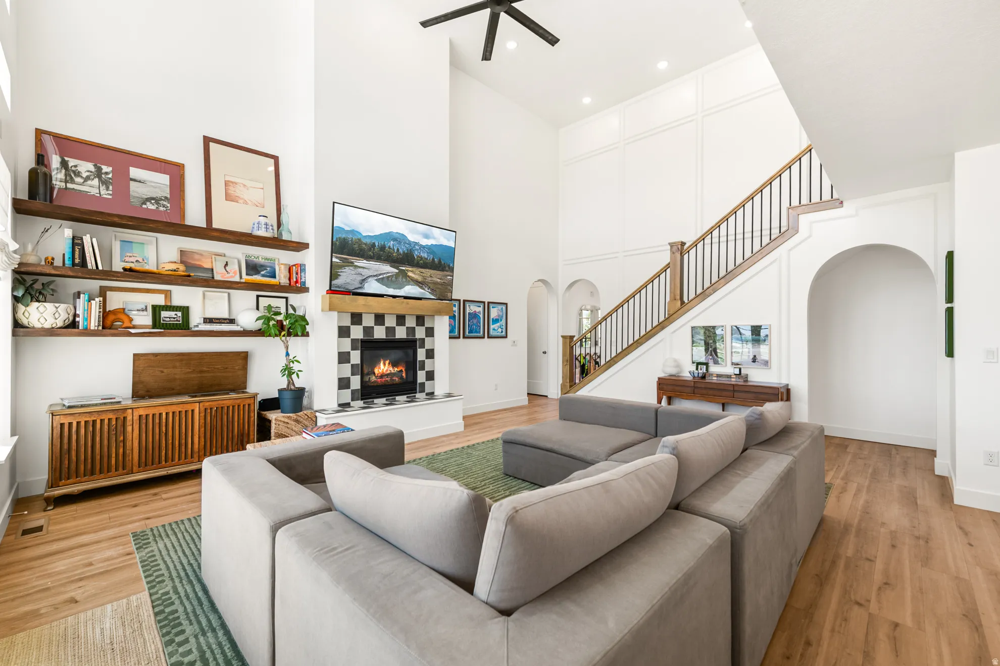 Soaring two-story living space featuring a fireplace with checkerboard tile surround and a wood mantel