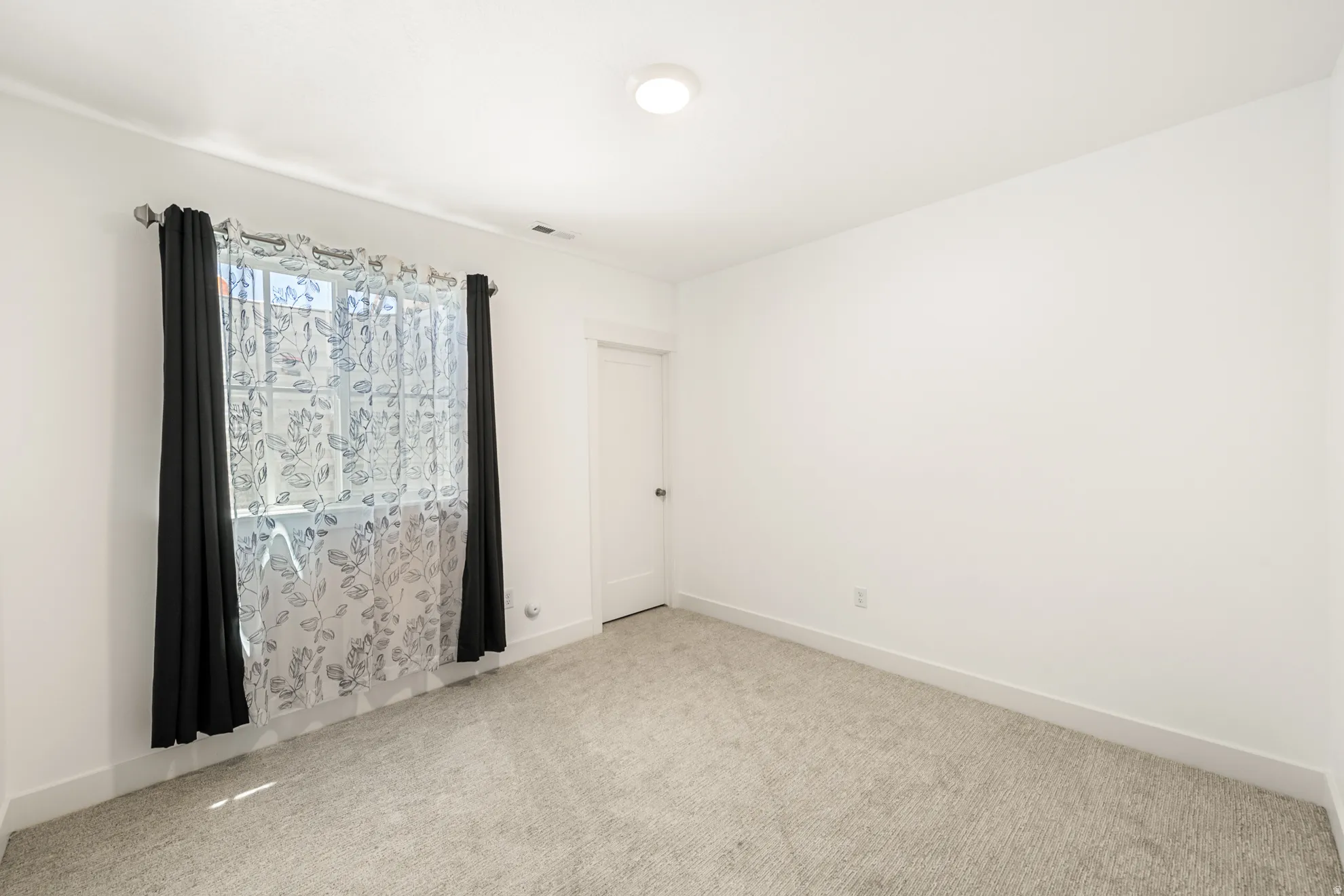 Carpeted room featuring a window with a curtain rod, a flush-mount ceiling light, and white trim