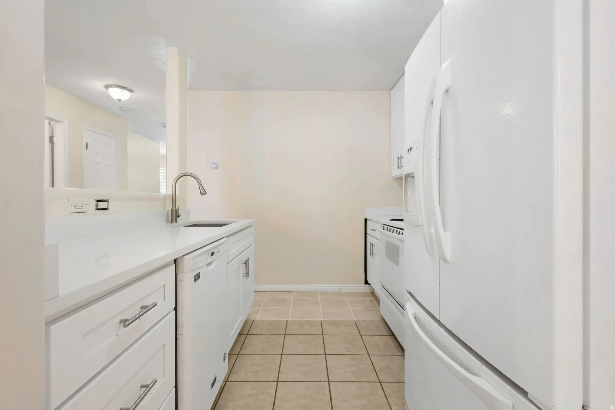 Kitchen with white cabinetry, stainless steel sink with gooseneck faucet, white appliances, and tiled flooring