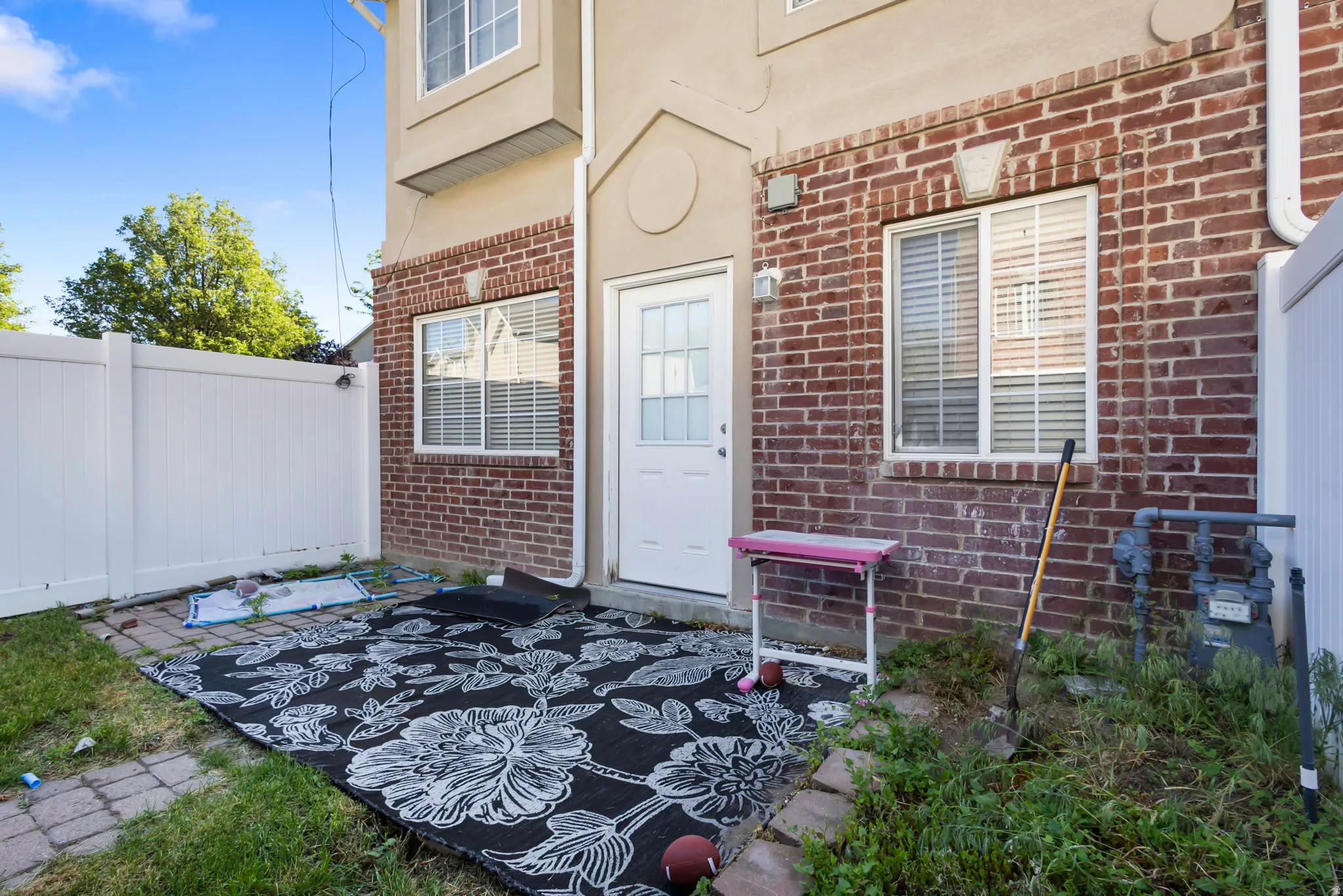 Brick exterior with upper-level stucco, white privacy fencing, and a ground-level patio area