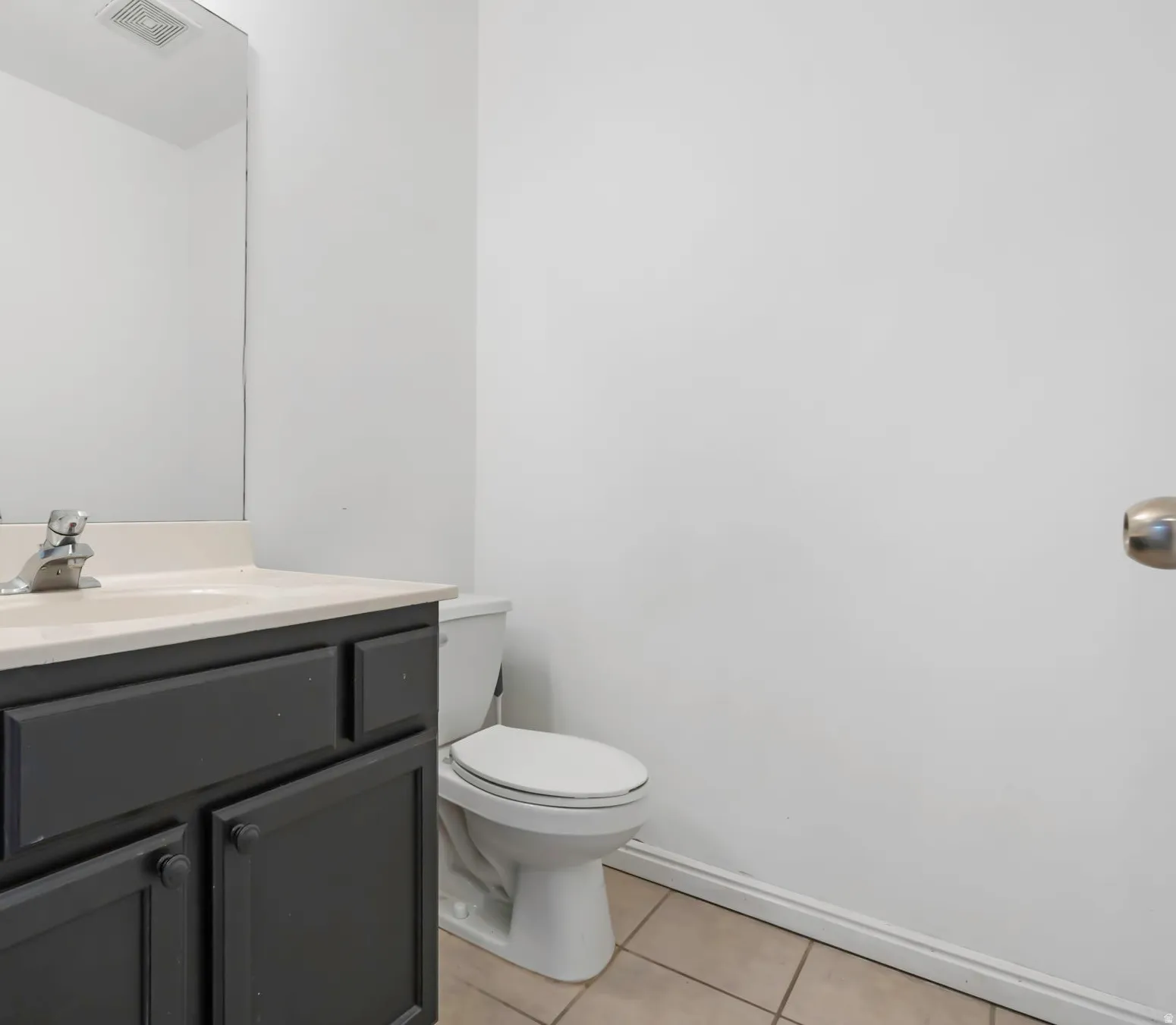 Bathroom featuring a dark gray vanity with matching knobs, an integrated sink, and a chrome faucet