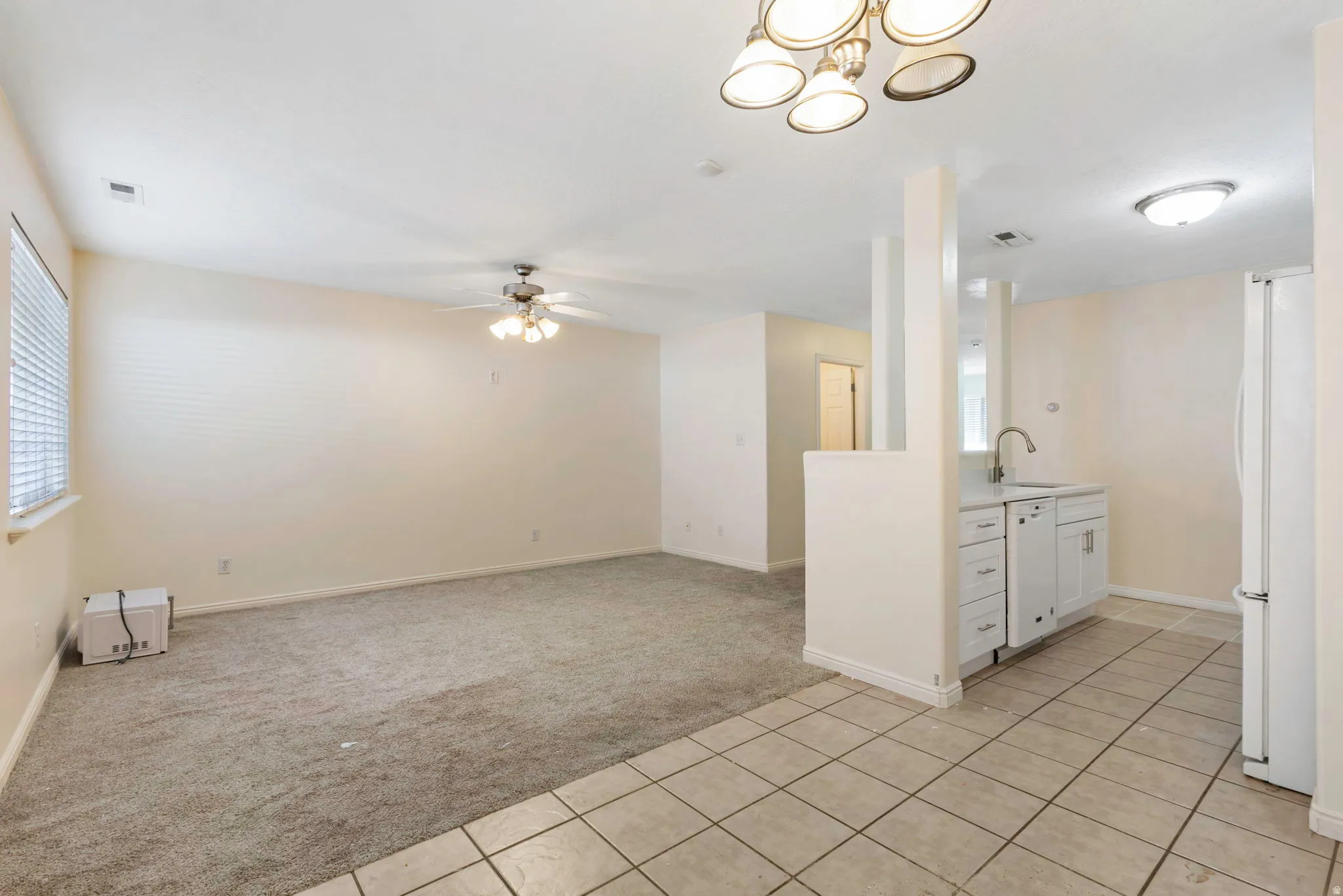 Open-concept living area with neutral carpet and an overhead ceiling fan