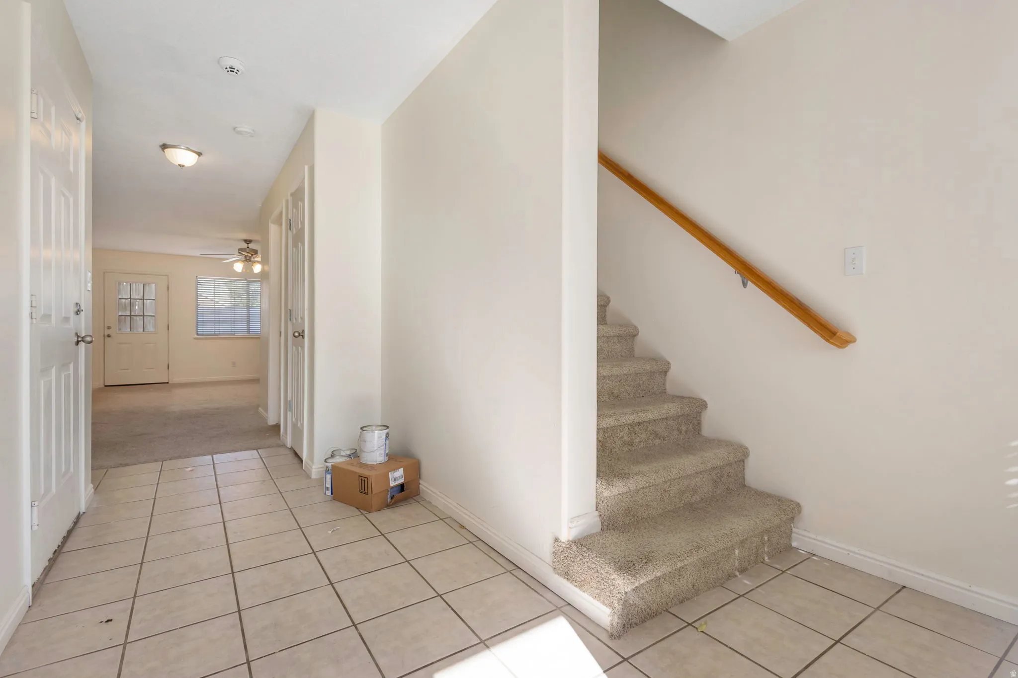 Foyer featuring ceramic tile flooring, a carpeted staircase with a wood handrail, and white paneled doors