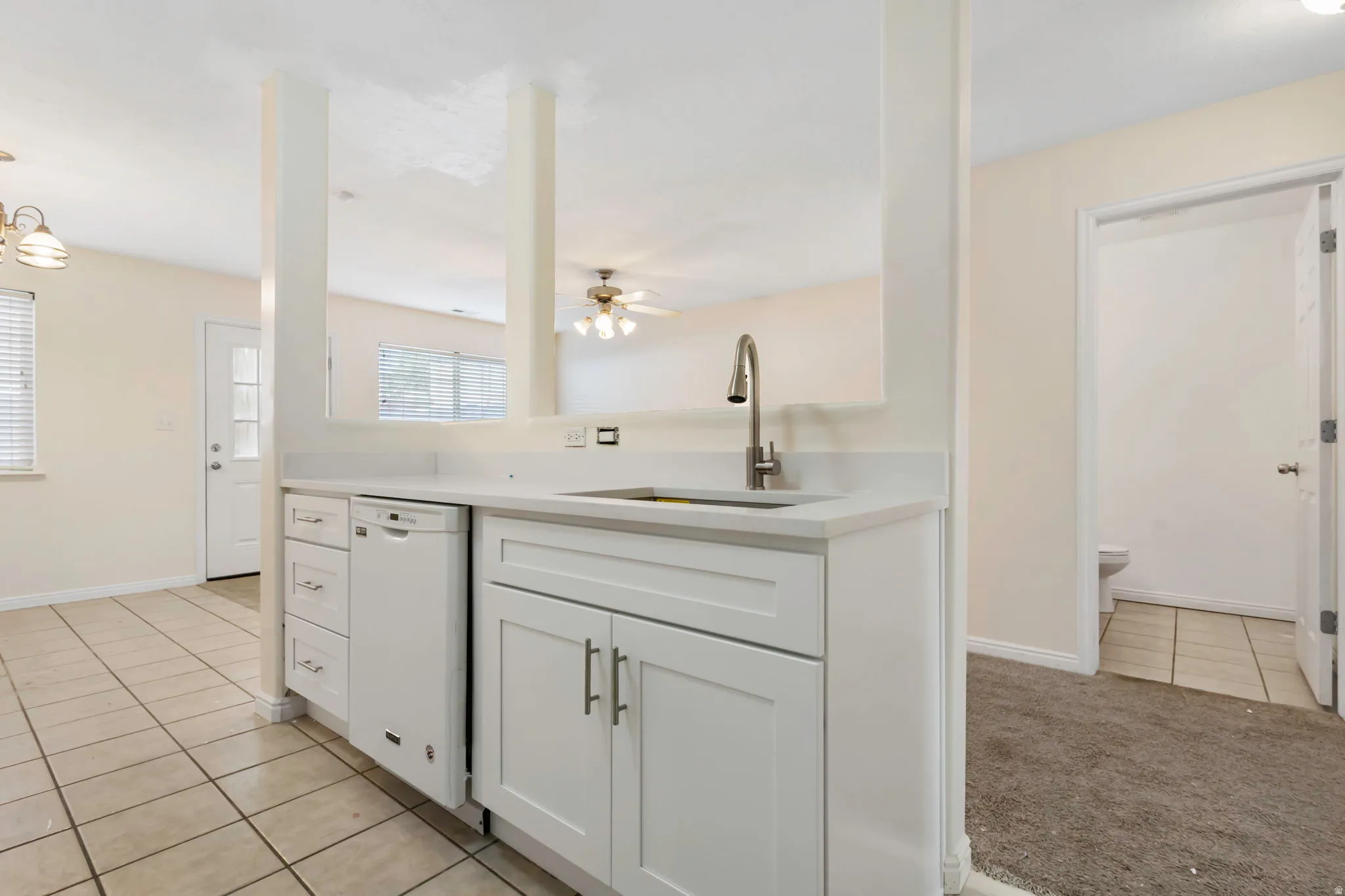 Kitchenette featuring white cabinetry, a built-in dishwasher, and a stainless steel faucet