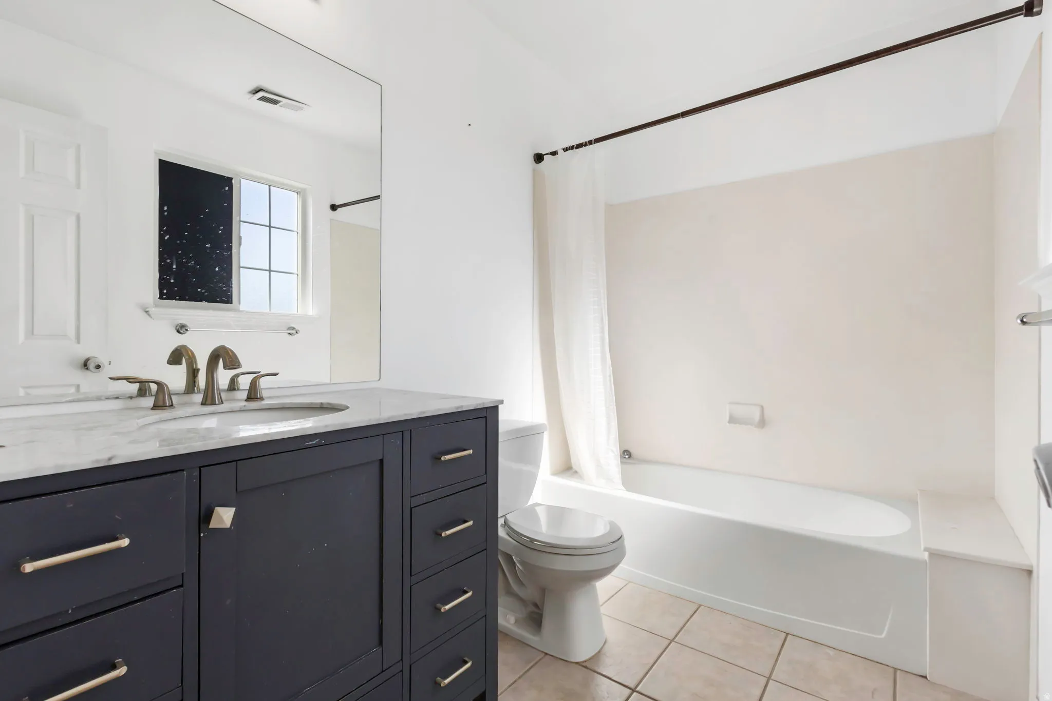 Bathroom featuring a dark wood vanity with a light-colored countertop, dual undermount sinks, and bronze-finish faucets
