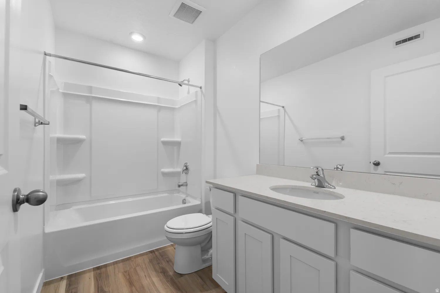 Full bathroom featuring a single-sink vanity with light-colored countertop, integrated mirror, and a white tub and shower combination with chrome fixtures