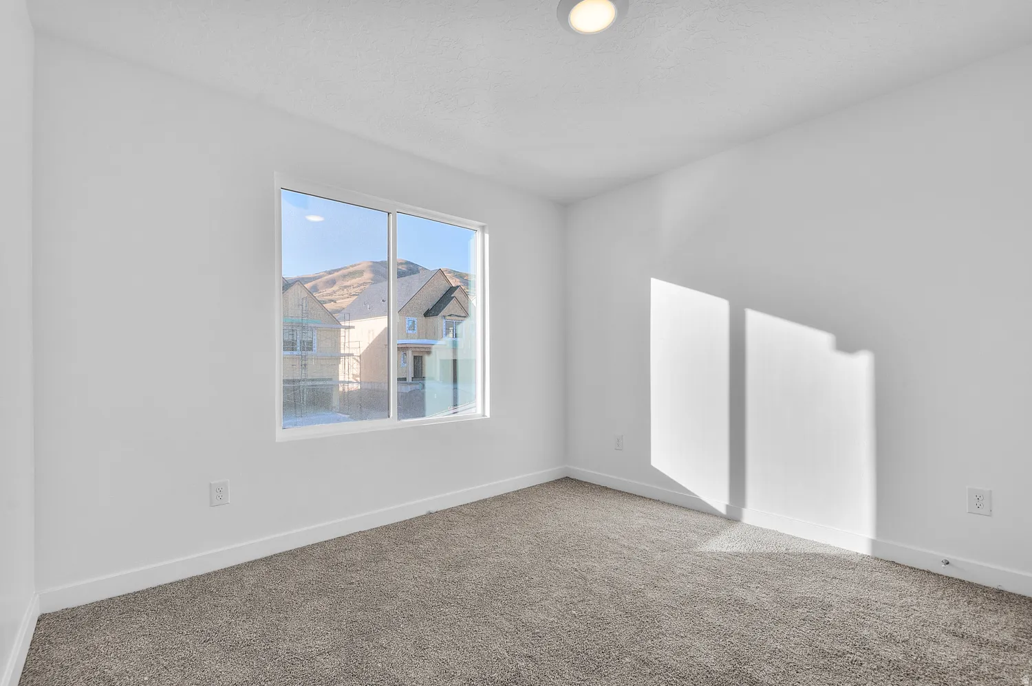 Bright interior room featuring a large window, recessed lighting, white walls, gray carpeting, and white baseboards