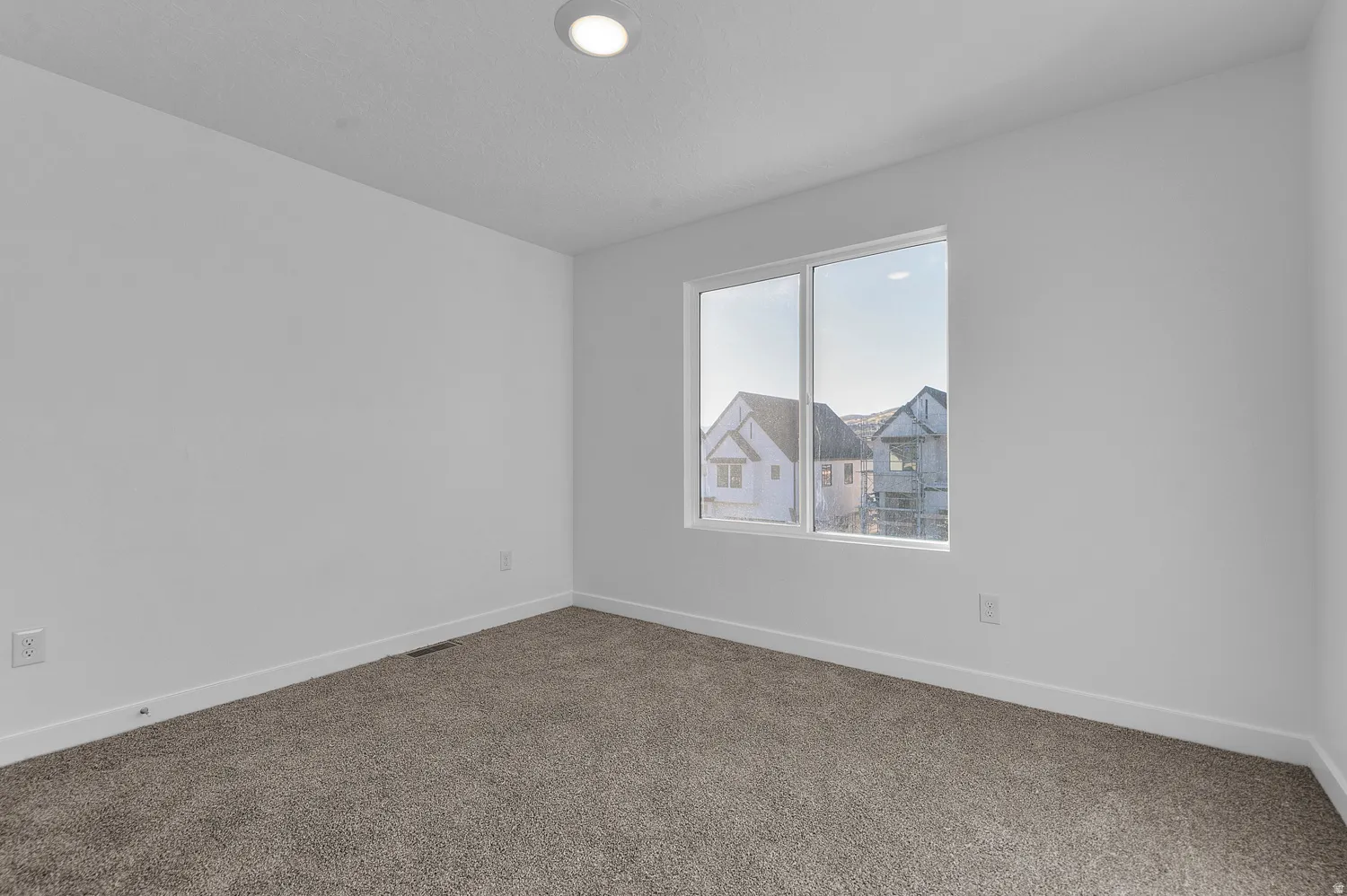 Bright room with neutral carpet flooring, white walls, and a recessed ceiling light