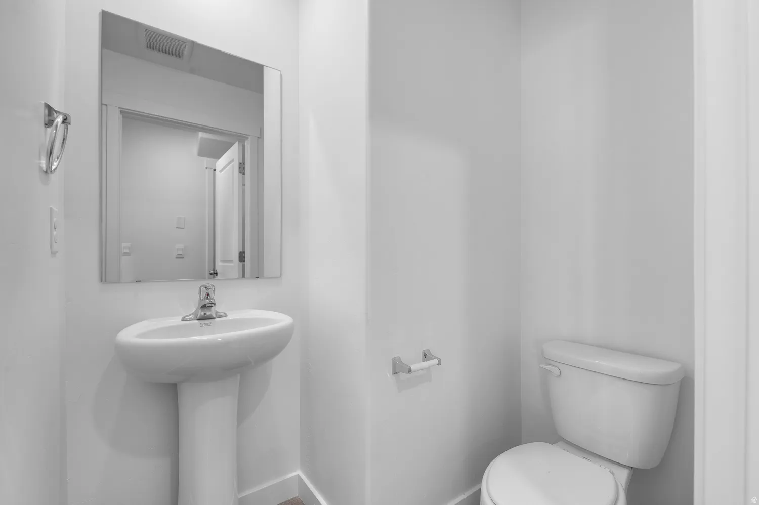 Contemporary powder room featuring a pedestal sink with chrome faucet, wall-mounted mirror, and a white toilet