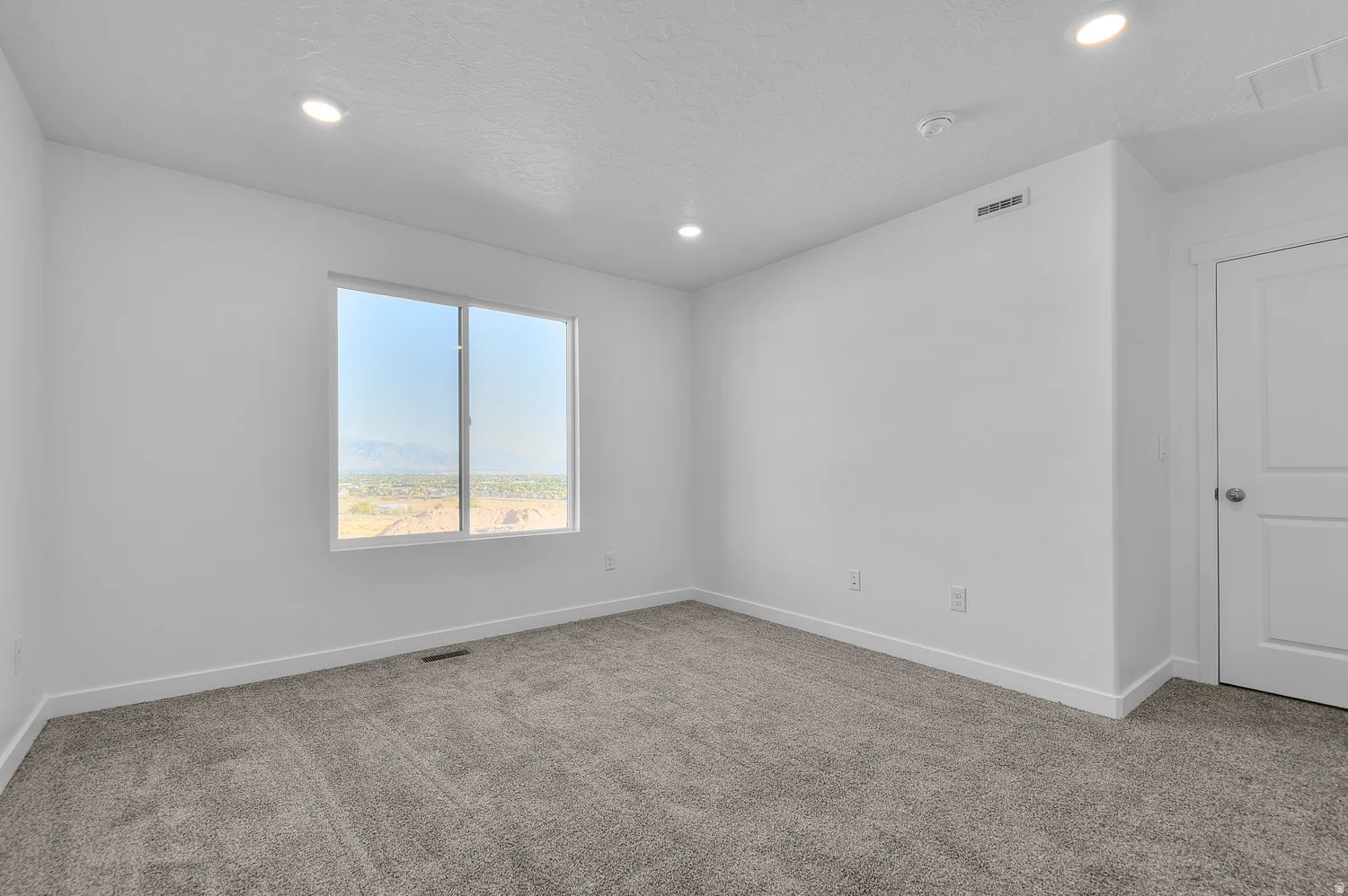 Carpeted room featuring a large window, recessed lighting, white walls, and white trim