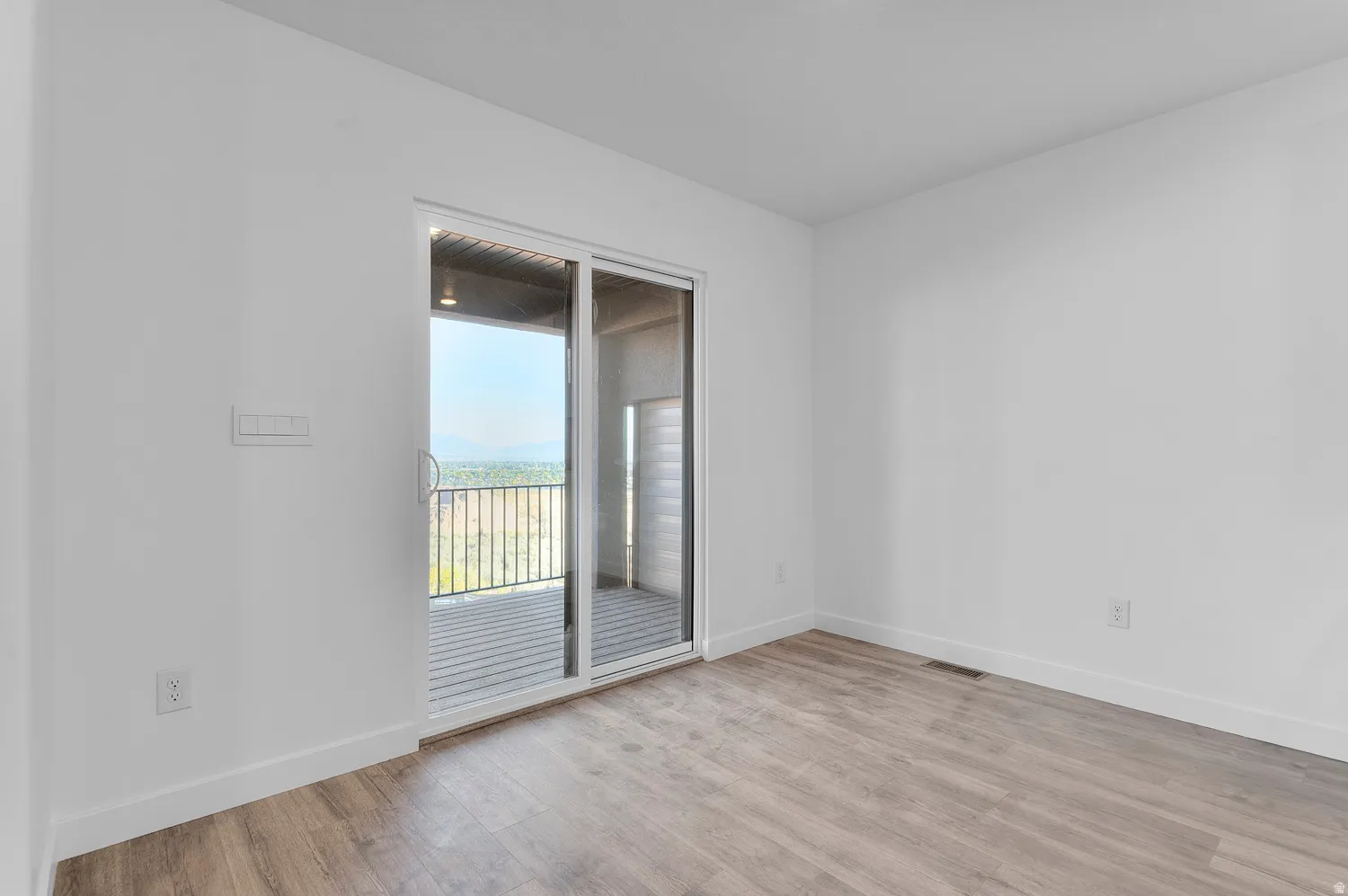 Interior room featuring a sliding glass door opening to an outdoor balcony with metal railings