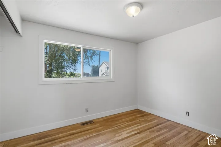 Wood-finish flooring, white walls, and a fixed window