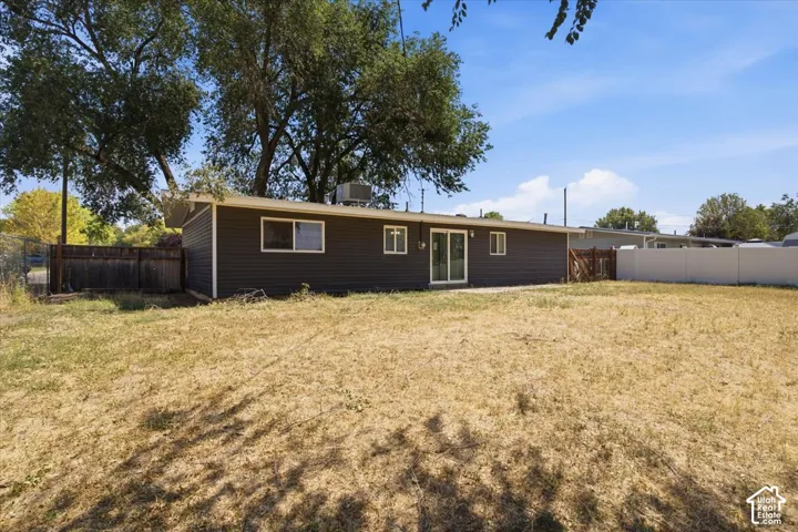 Expansive property featuring a dark-toned exterior, multiple windows, sliding glass door, and a white privacy fence