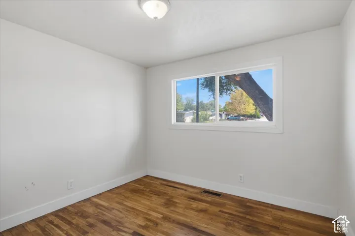 White walls, wood-finish flooring, white window trim, and a ceiling-mounted light fixture