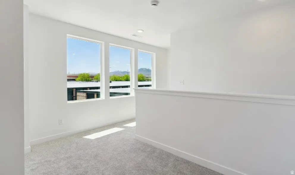Upper level landing with three large windows, white walls, light gray carpet, and recessed lighting