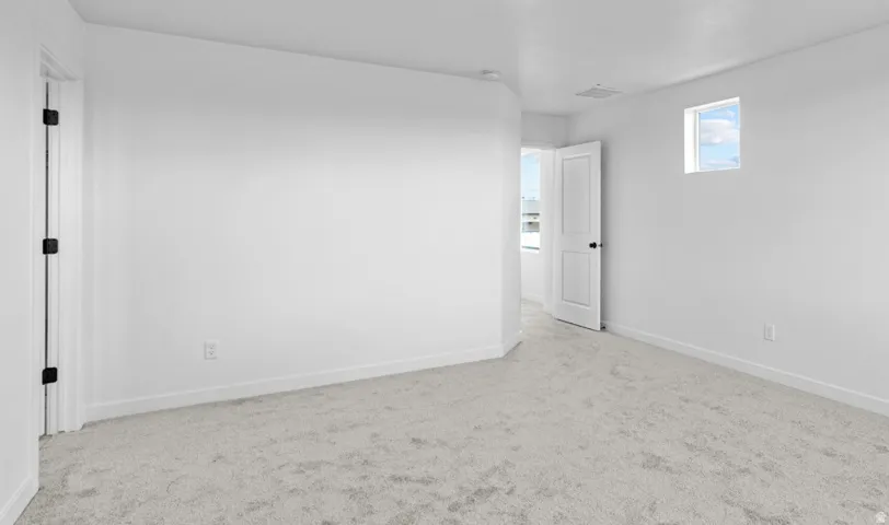 Carpeted room featuring a white interior door with black hardware, a high window, and neutral wall tones
