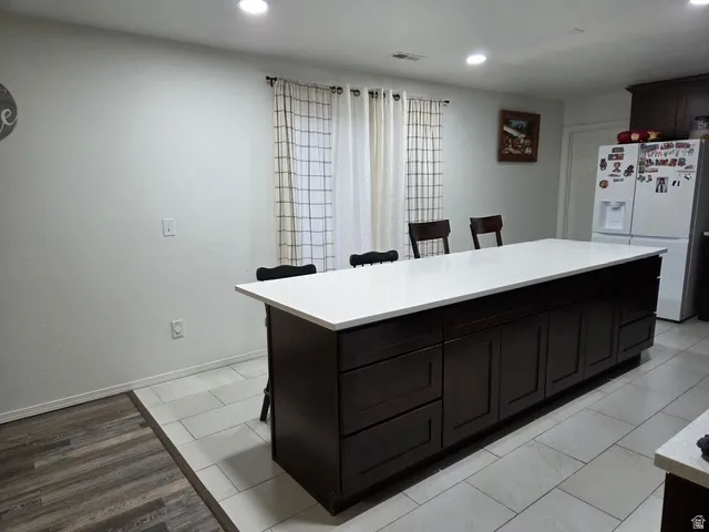 Spacious kitchen island featuring a white countertop, dark wood-finish cabinetry, and recessed lighting
