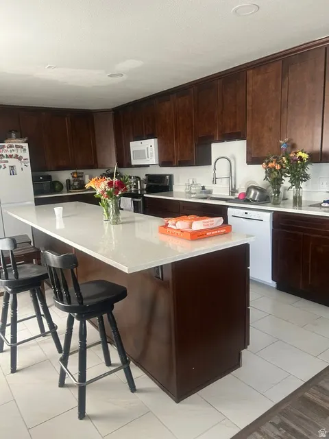 Spacious kitchen featuring dark wood cabinetry, light-toned countertops, and a large center island with integrated seating