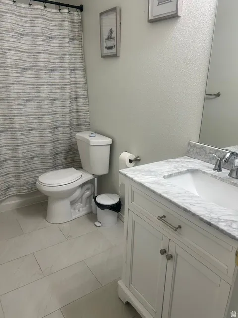 Bathroom featuring a white vanity with a stone countertop, an integrated sink, and brushed nickel hardware
