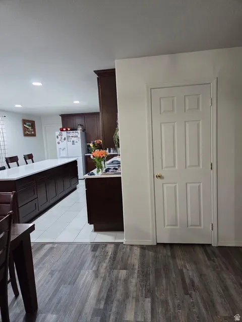 Kitchen area featuring recessed lighting, dark wood cabinetry, and a large central island with a light-toned countertop