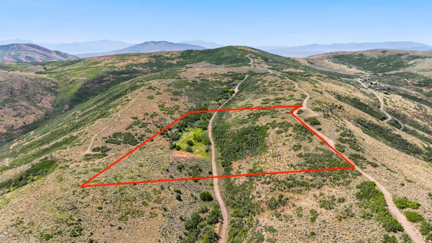 Expansive mountain property featuring varied topography, natural vegetation, and distant mountain ranges