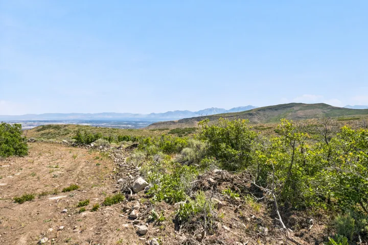 Expansive natural landscape featuring distant mountain ranges and a city skyline