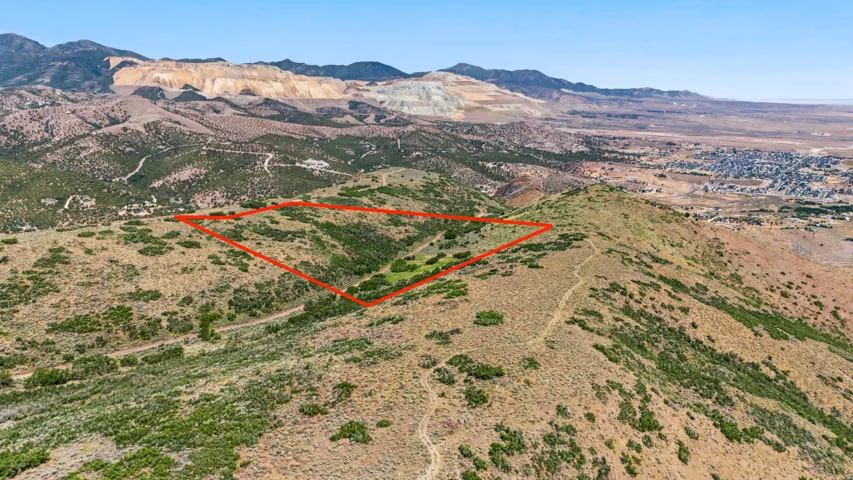 Expansive undeveloped land parcel outlined in red, featuring natural terrain, varied vegetation, and distant mountain ranges