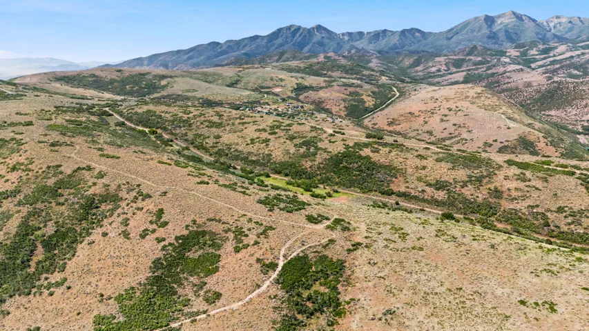 Expansive mountainous terrain featuring natural vegetation and winding dirt paths
