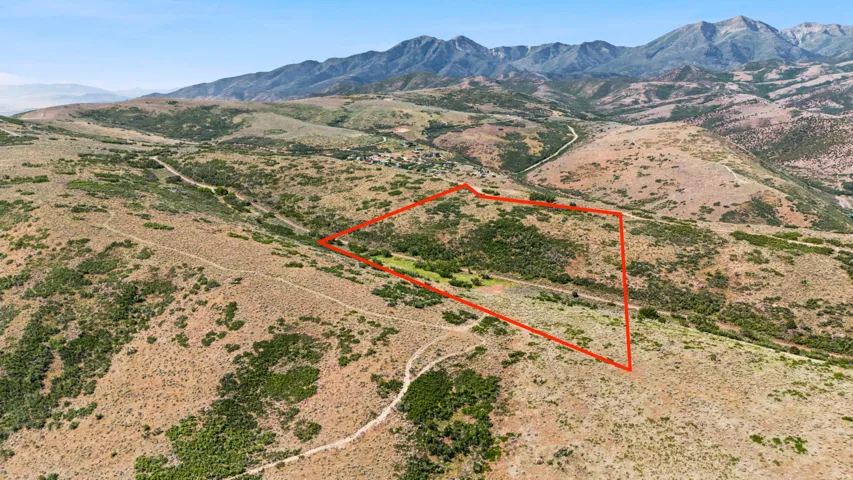 Expansive mountain property featuring varied terrain, natural vegetation, and distant mountain ranges