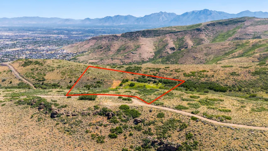 Expansive hillside property featuring a defined parcel boundary, natural terrain, and a distant cityscape