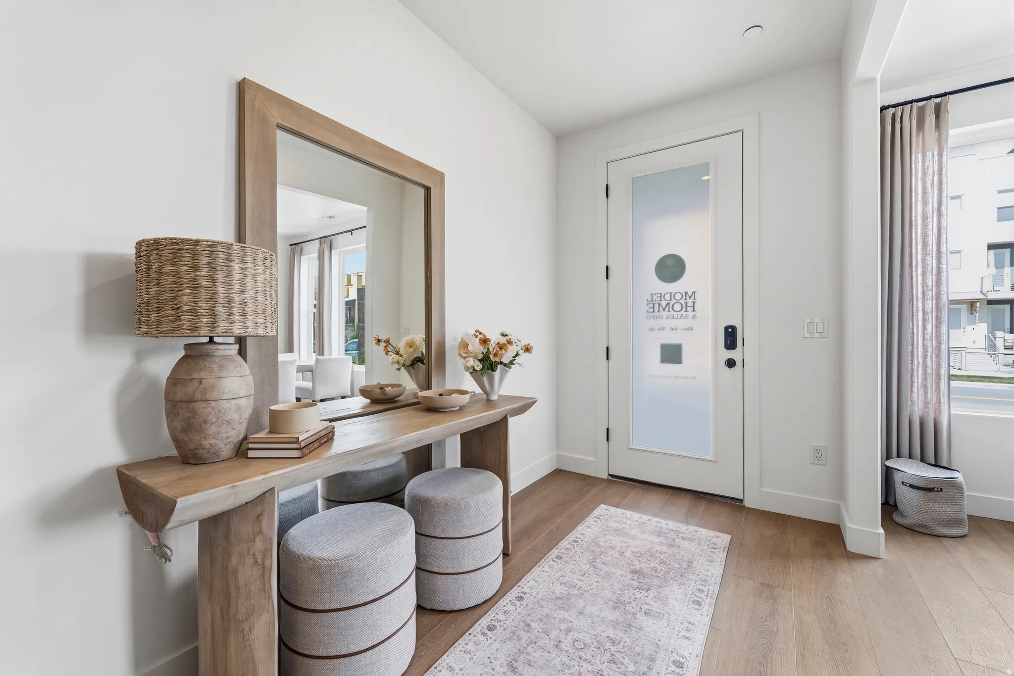 Entryway featuring wood-finish flooring, a white glass-paneled door, and a prominent window with drapes