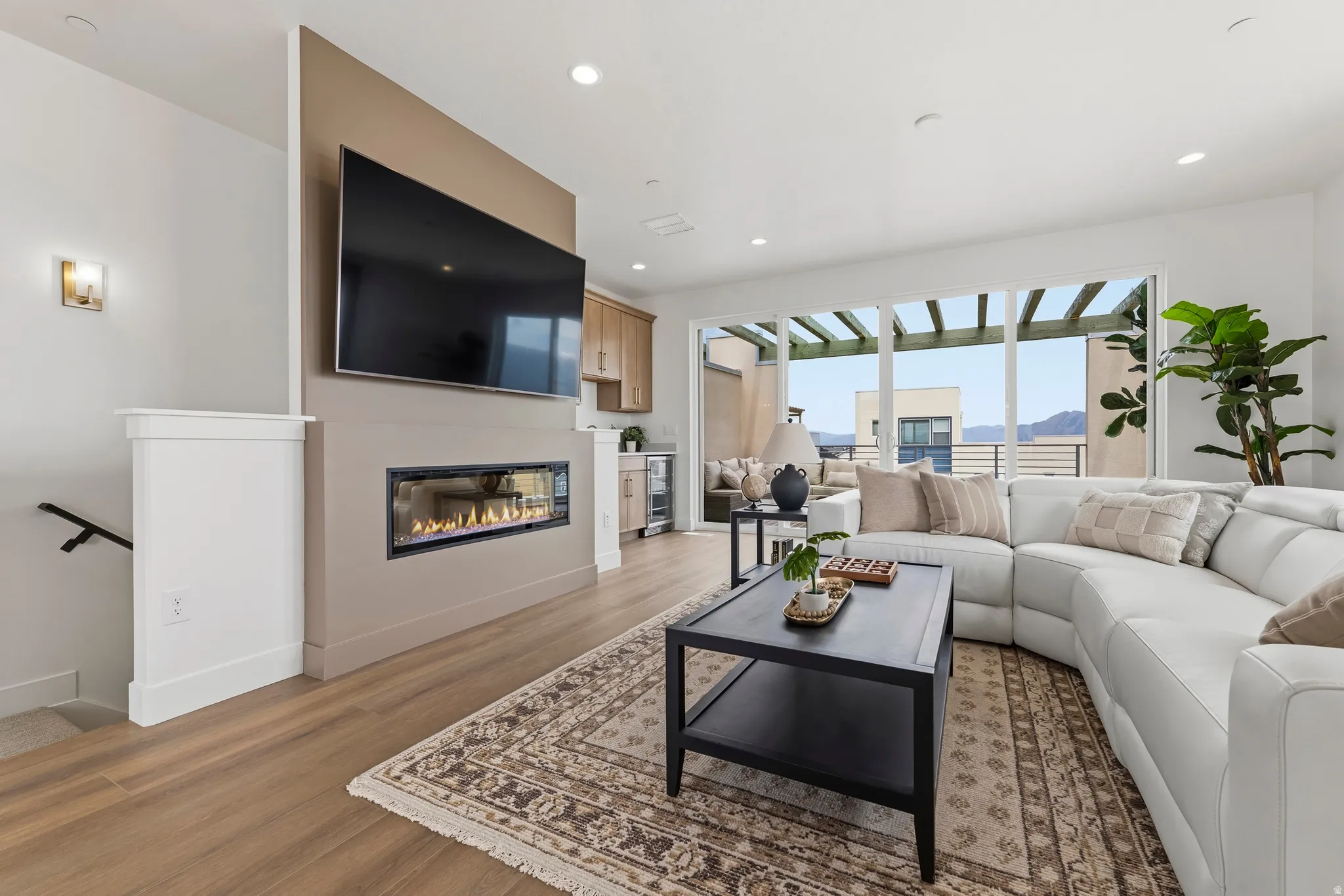 Living area featuring a linear fireplace, wood-finish flooring, recessed lighting, and a built-in wet bar