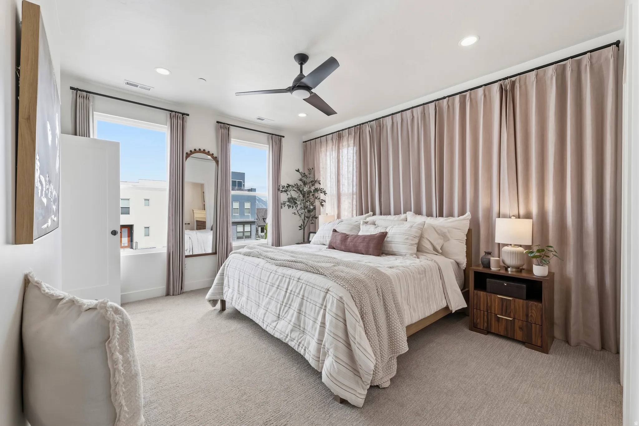 Bedroom featuring light-toned carpeting, dual windows with ample natural light, and a ceiling fan with integrated lighting