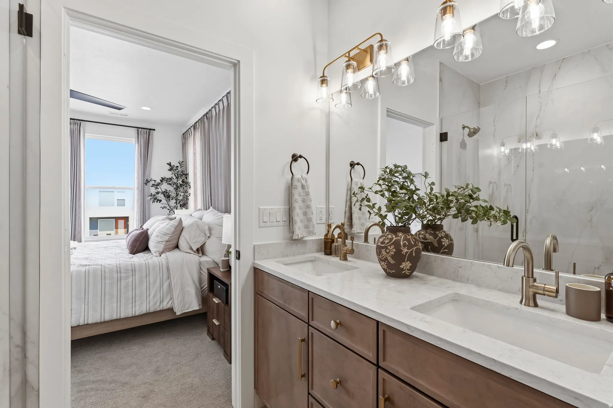 Dual vanity with integrated sinks, brushed gold fixtures, and a large frameless mirror