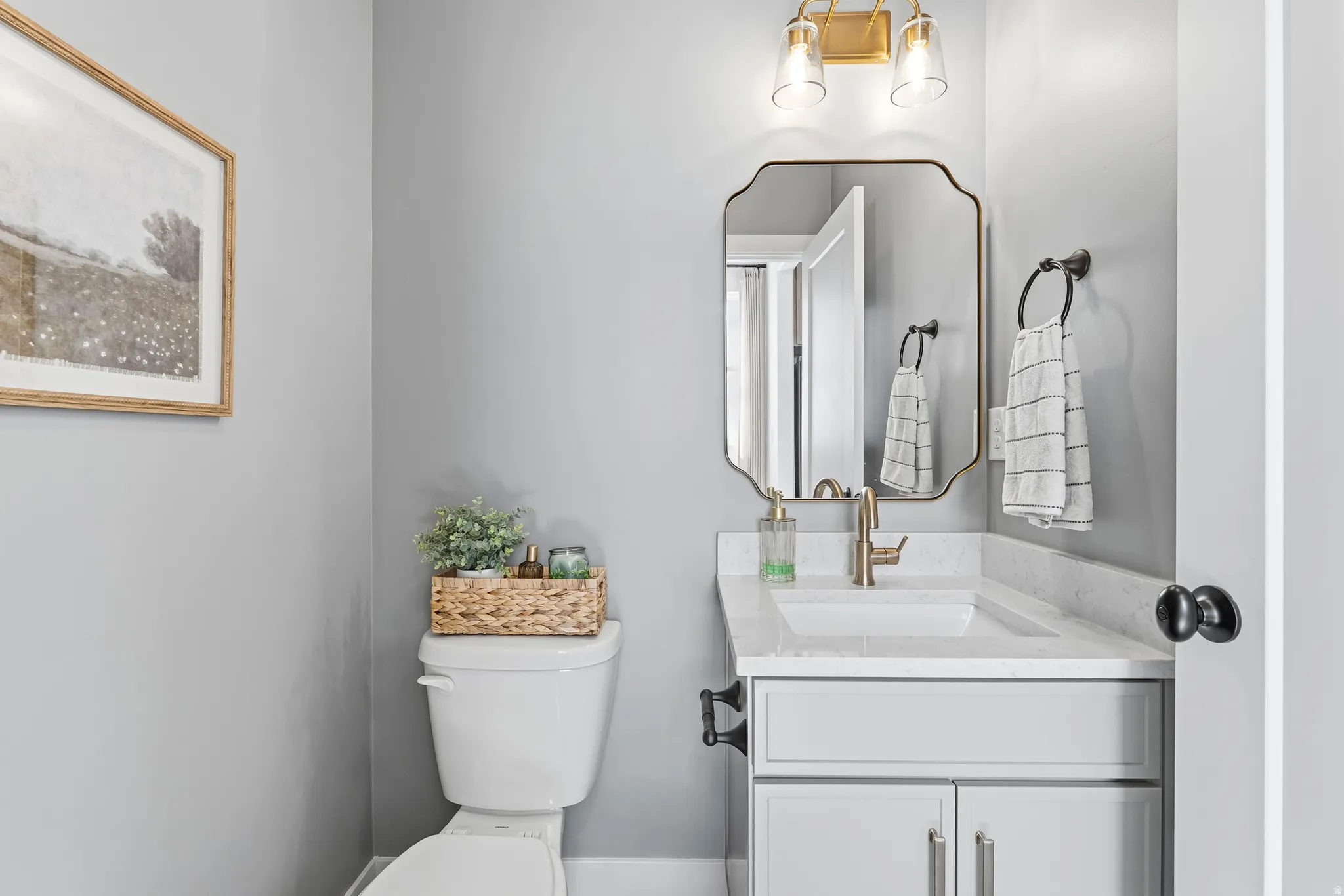 Bathroom featuring a vanity with a white countertop, undermount sink, and brass-finish faucet