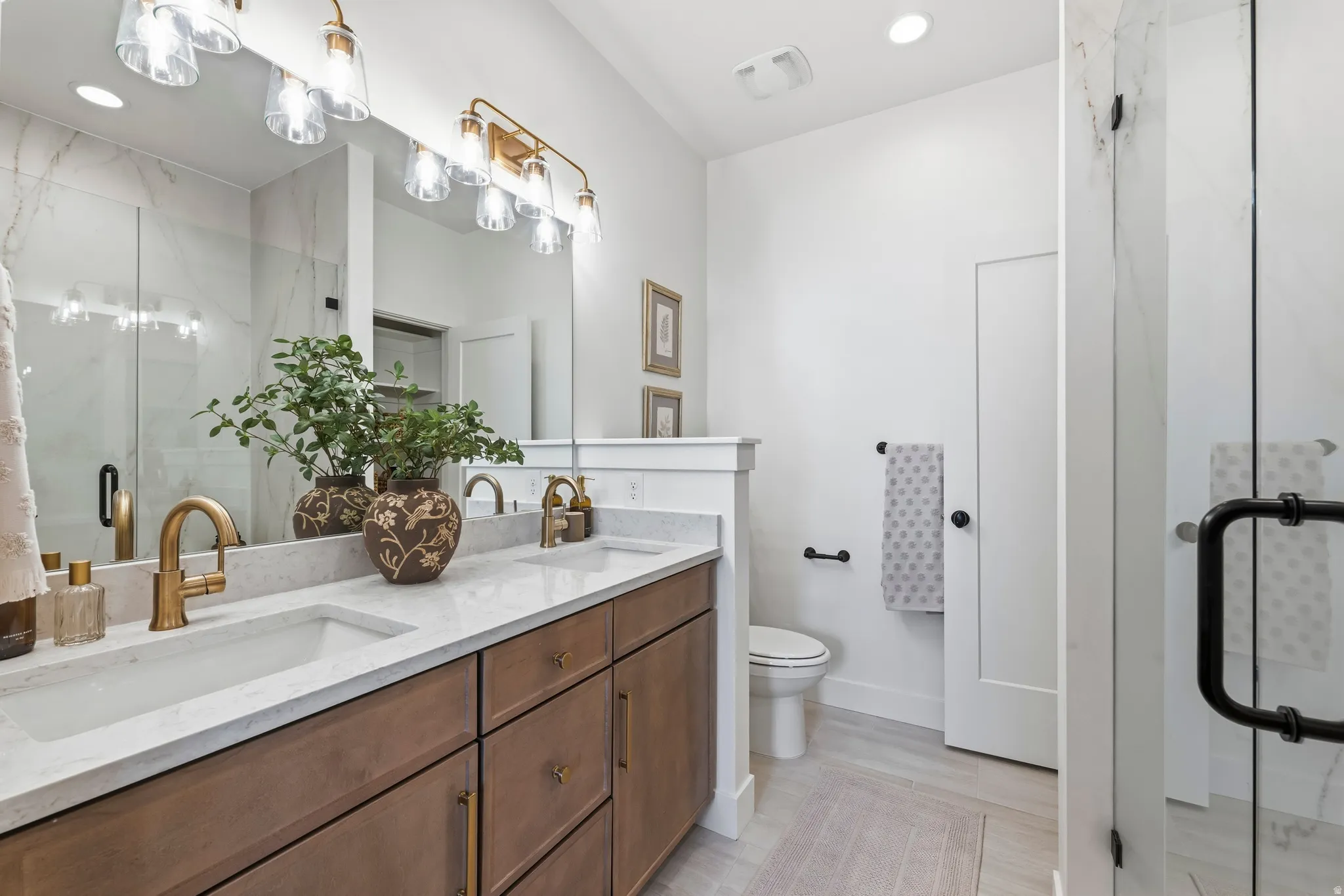 Double vanity with undermount sinks, stone countertops, and brass-finish fixtures