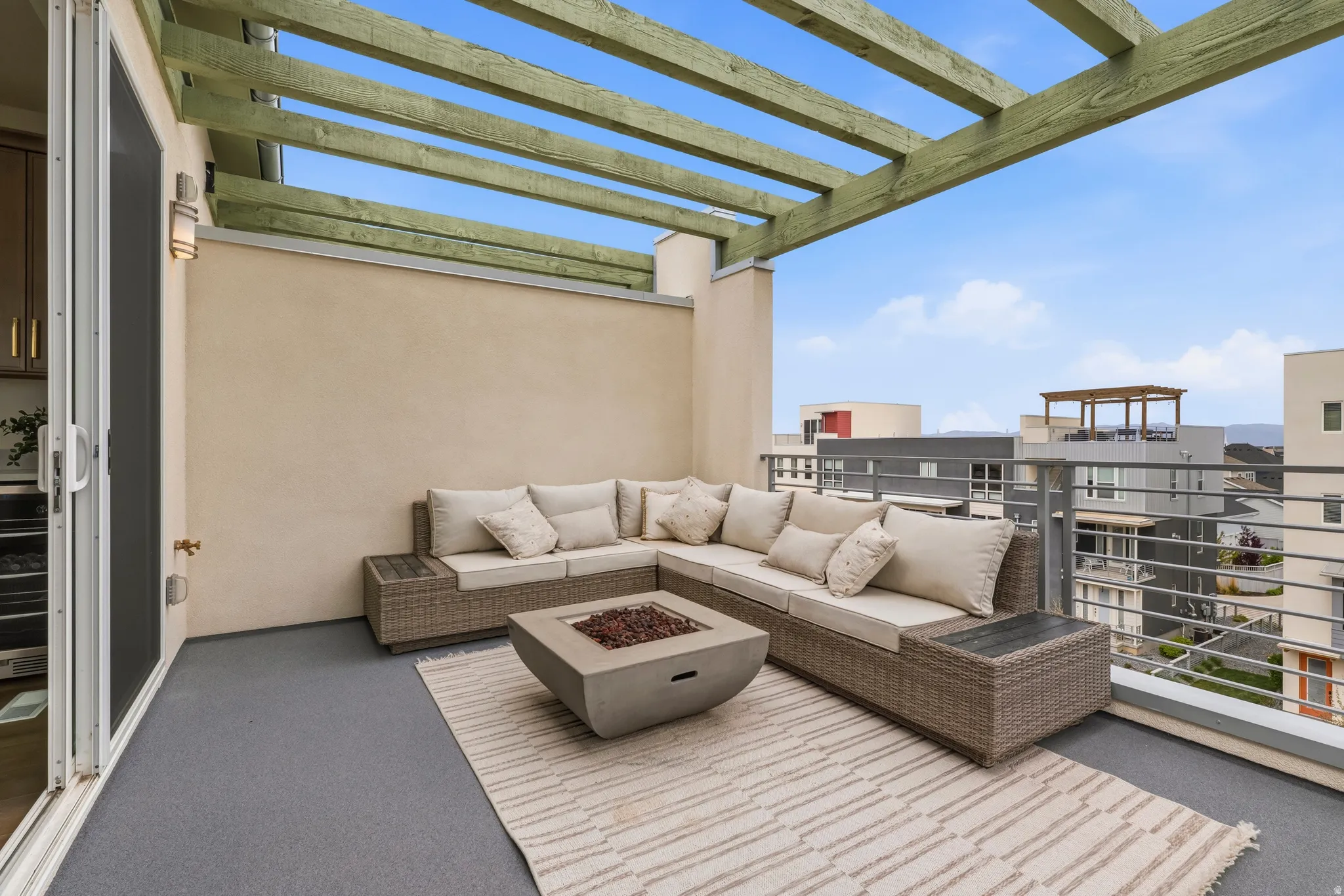 Outdoor deck featuring a wood pergola, stucco exterior, metal railing, and a sliding glass door
