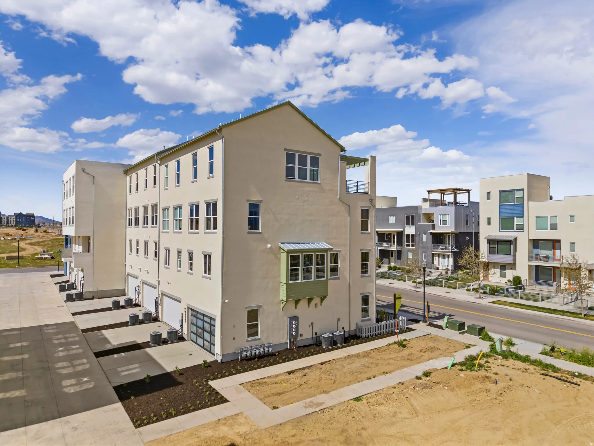 Contemporary multistory building featuring a light-toned stucco exterior, multiple window placements, and an accessible rooftop terrace