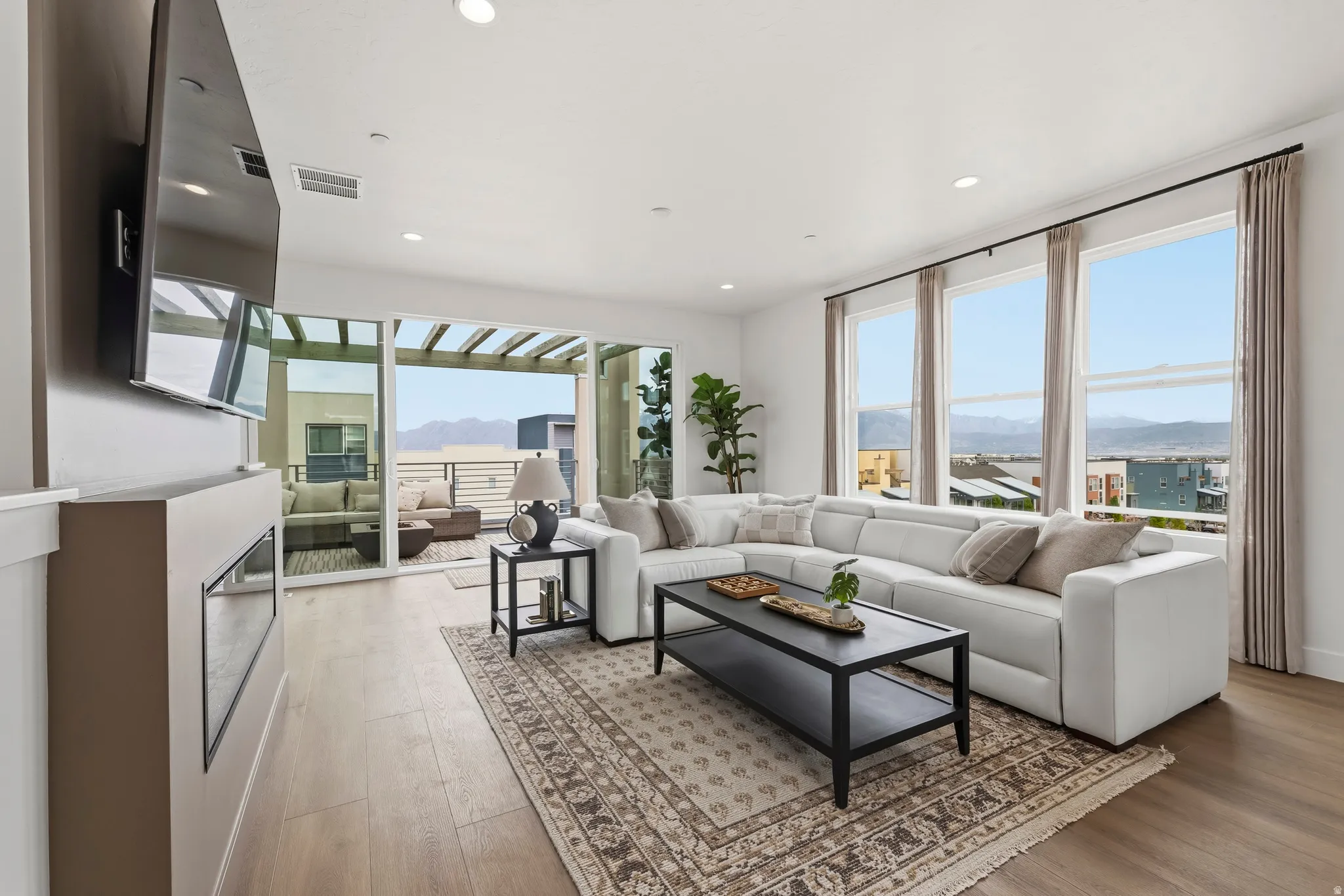 Living area featuring wood-finish flooring, recessed lighting, and a linear electric fireplace