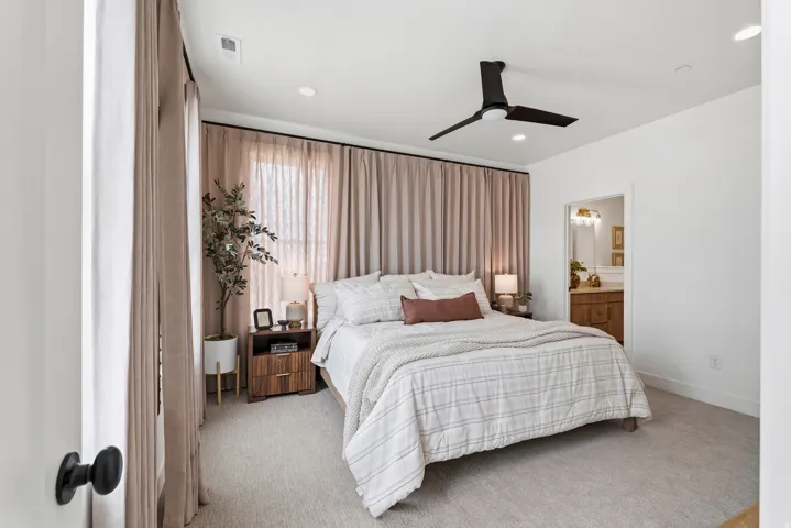 Carpeted bedroom featuring a large window with full-height drapes, recessed lighting, and a contemporary ceiling fan
