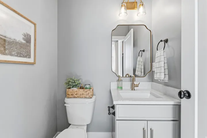 Bathroom featuring a vanity with a white countertop, undermount sink, and brass-finish faucet
