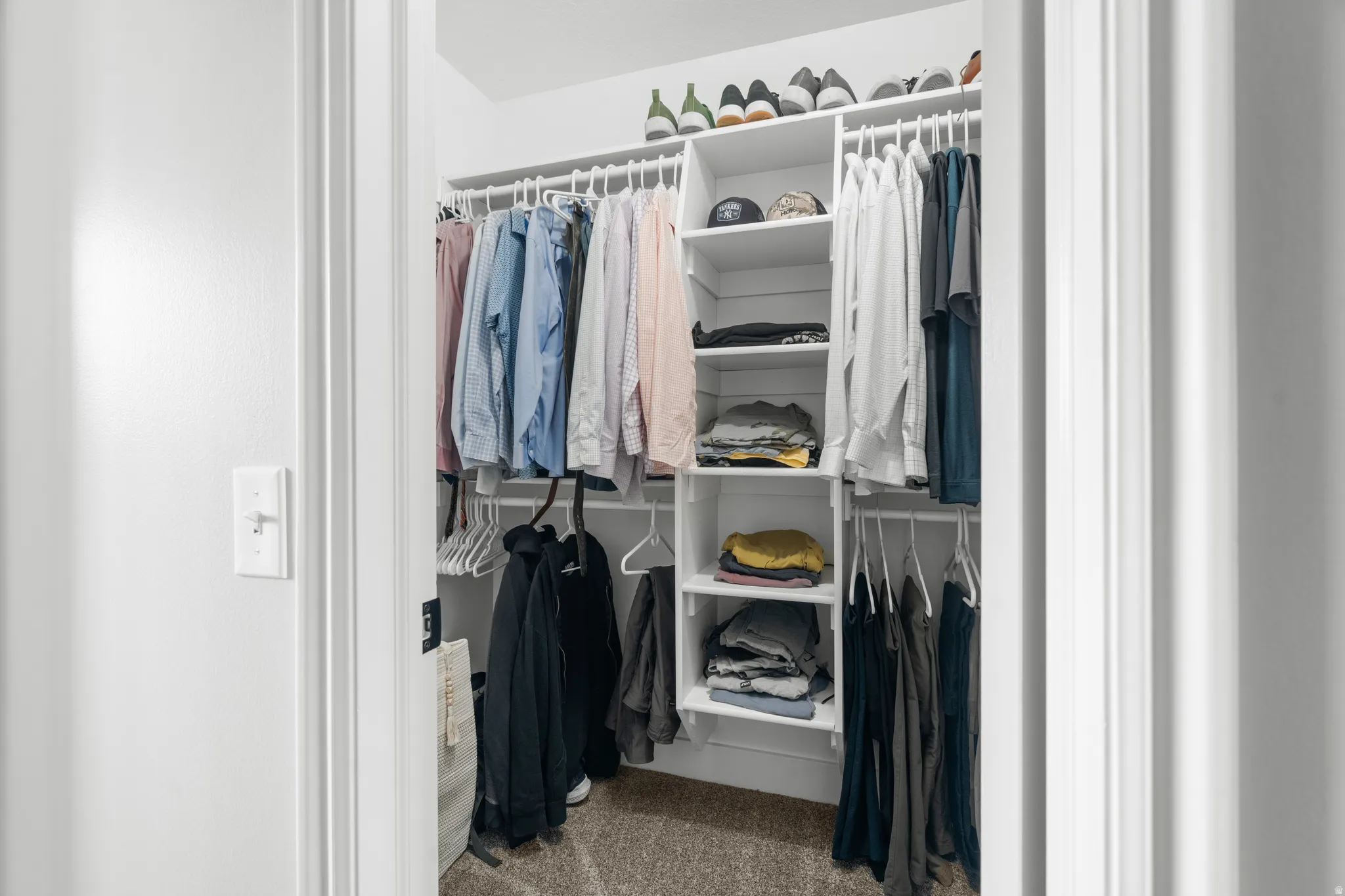 Primary dual walk-in closets featuring built-in shelving, multiple hanging rods, and neutral-toned carpeting