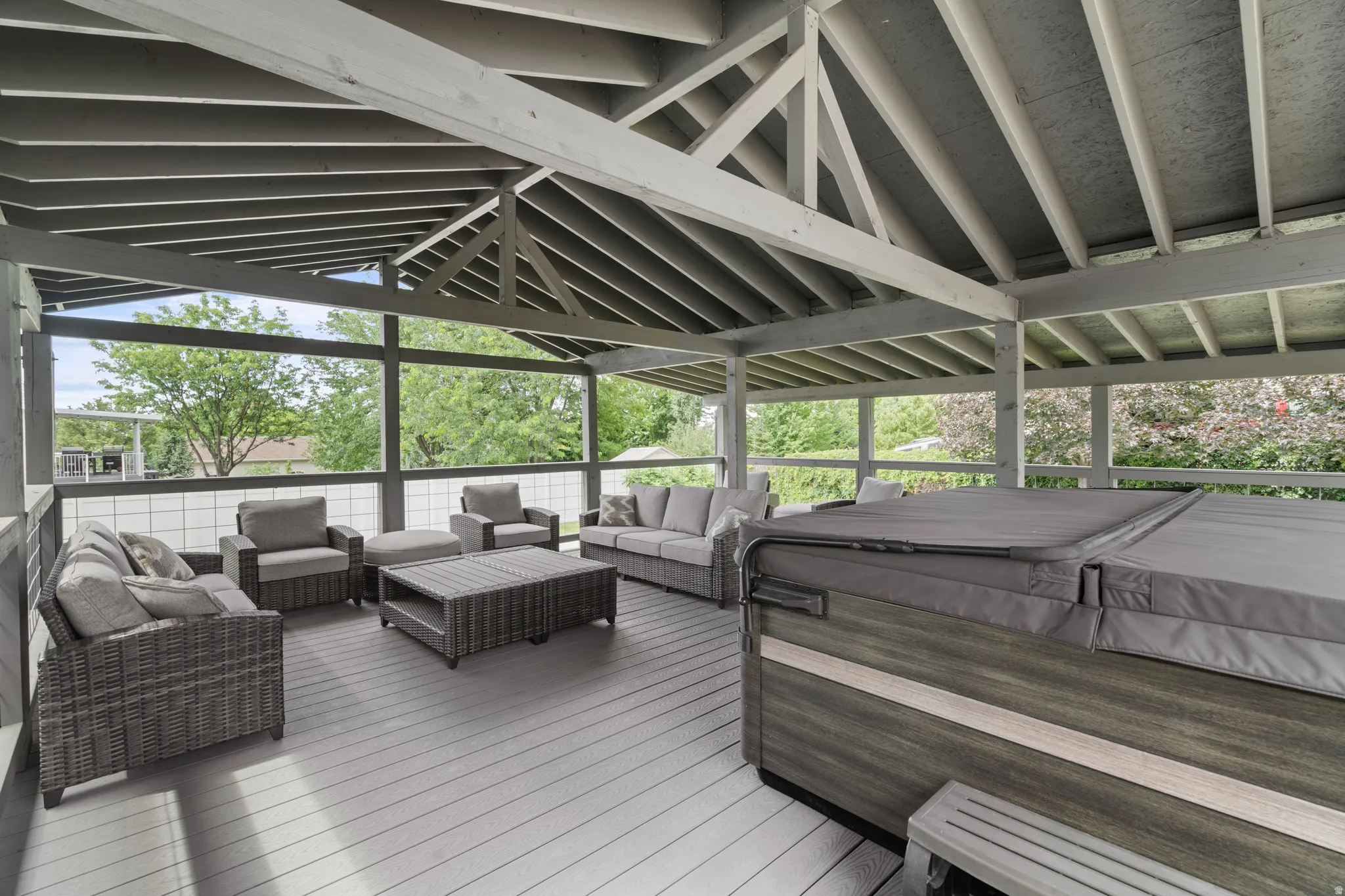 Custom-built covered gazebo deck with quality 6x6 construction, exposed beam ceiling, composite decking, and glass railings. Spacious design offers the perfect setting for outdoor gatherings and hot tub enjoyment