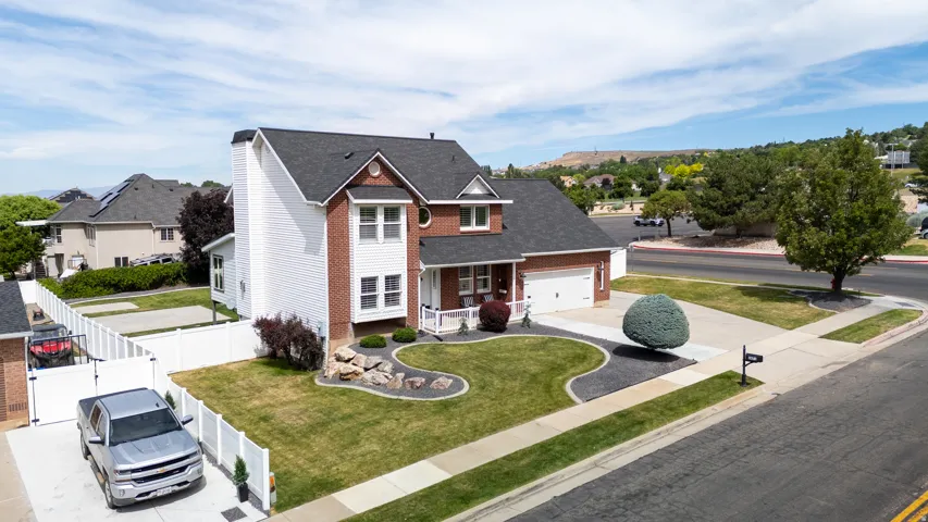 Aerial view of the brick and siding exterior featuring a covered front porch and an attached two-car garage
