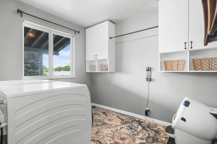 Utility laundry room with window, overhead cabinetry with laundry clothing rod