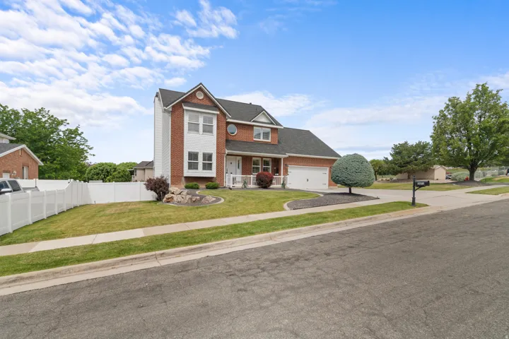 Traditional two-story residence featuring a brick facade with white siding accents and a contrasting dark shingle roof